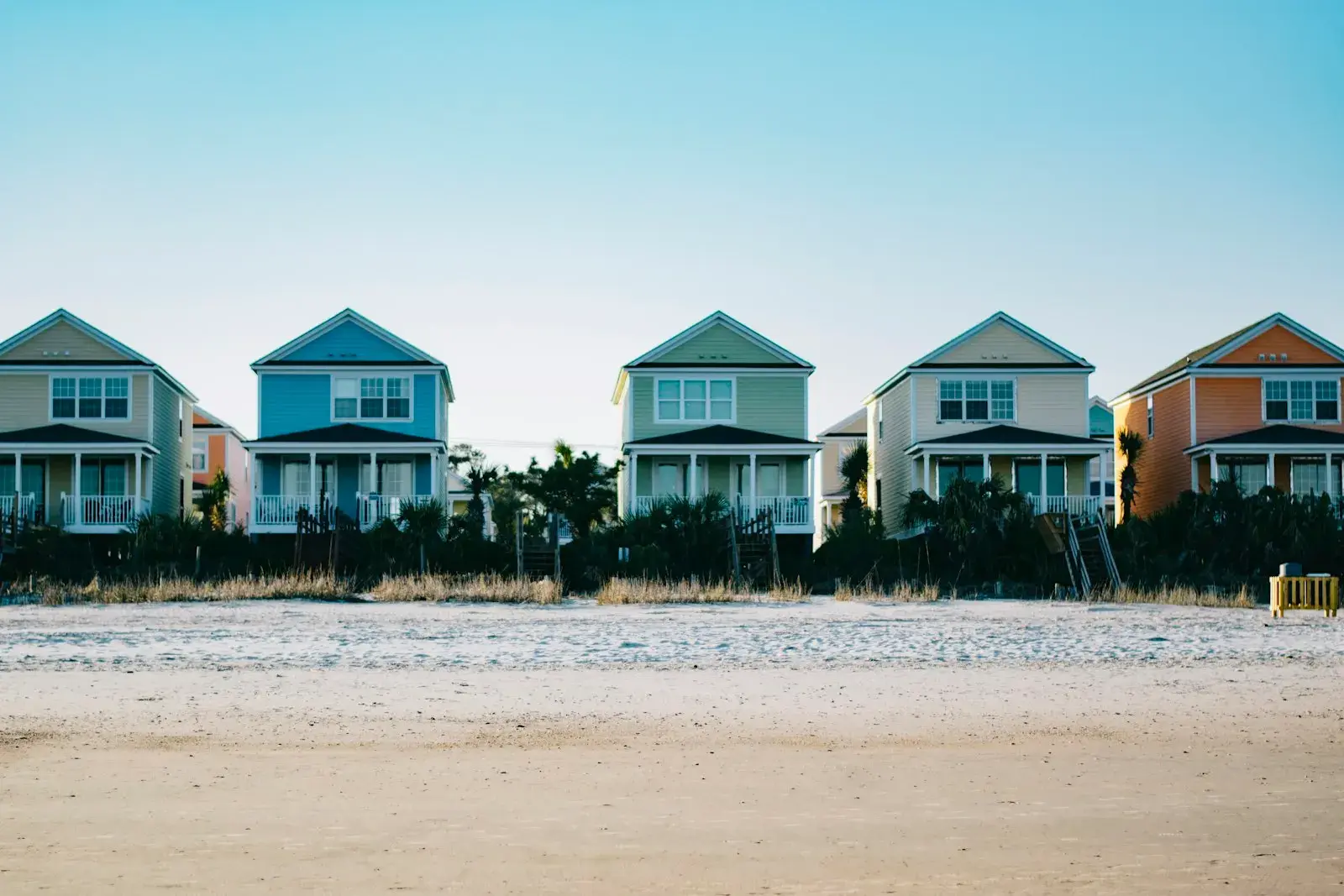 A row of five colourful two-storey holiday homes in a neat line.
