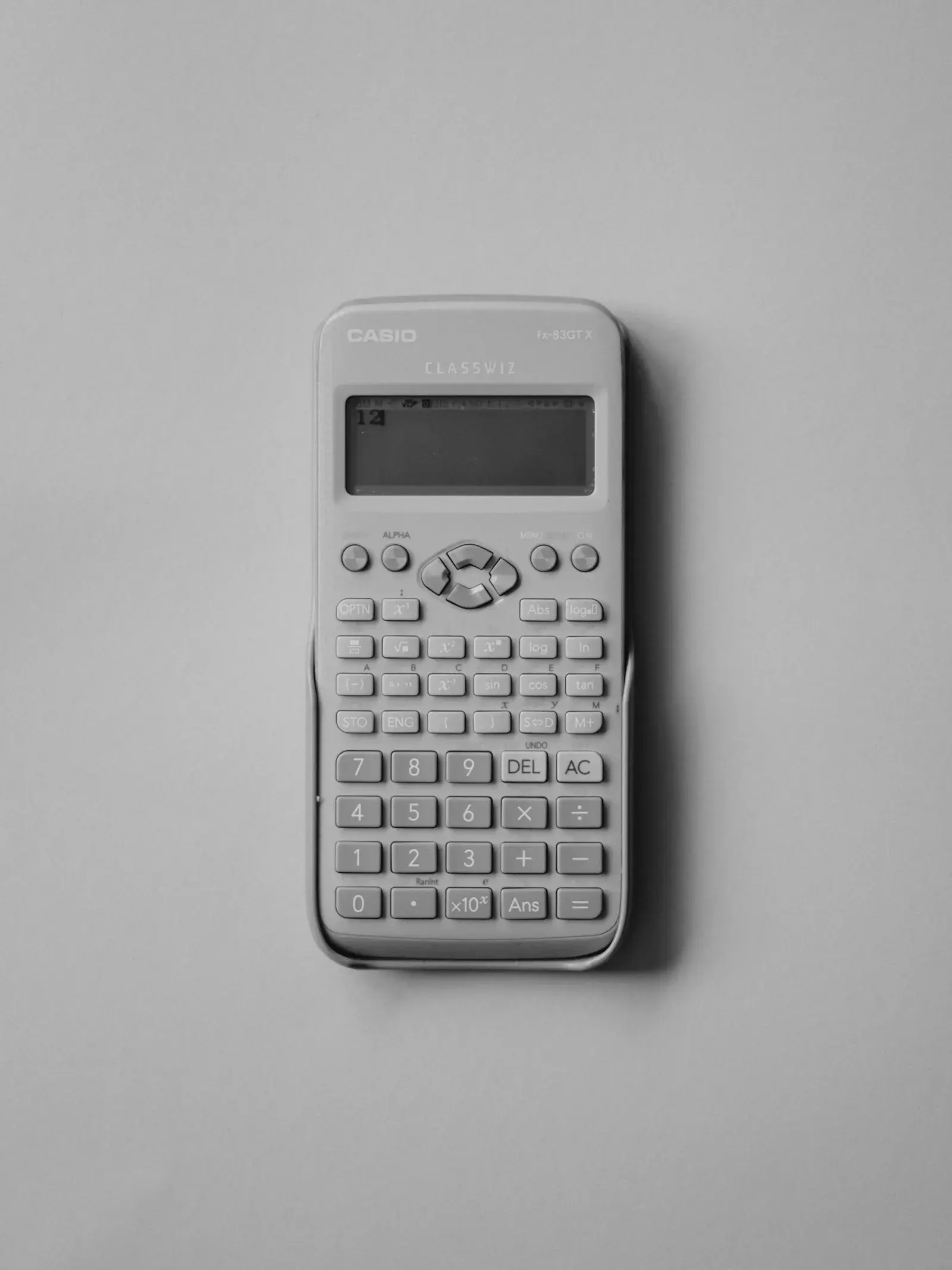 A white calculator lying on a grey surface.