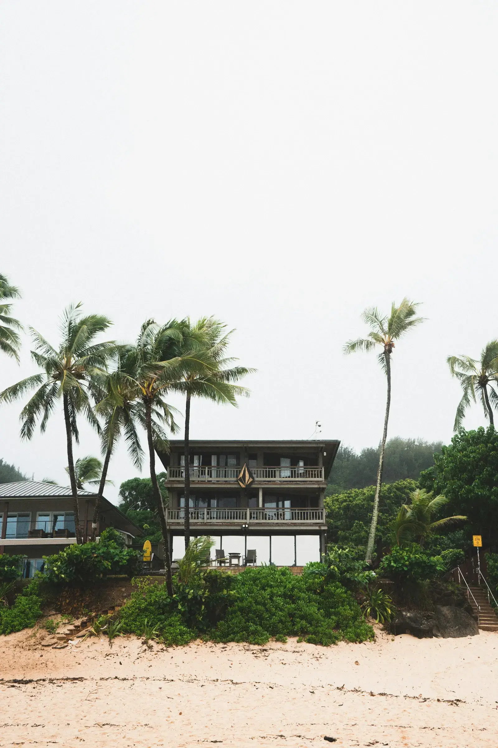 A wooden holiday house among palm trees, close to the sand.