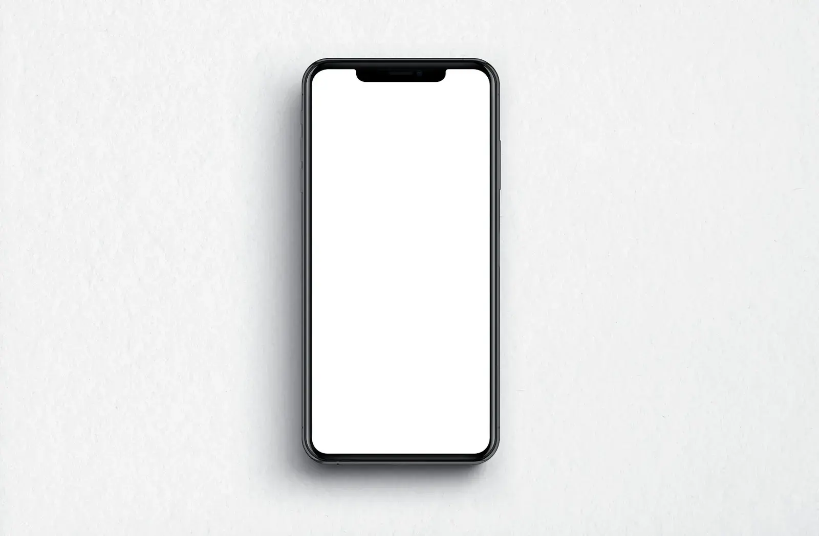 A black smartphone with a blank white screen lying on a light grey surface.