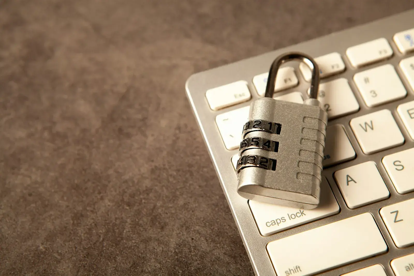 A combination padlock resting on a computer keyboard.