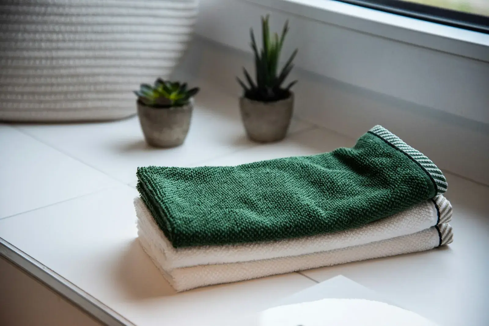 Folded towels on a shelf next to small potted plants.