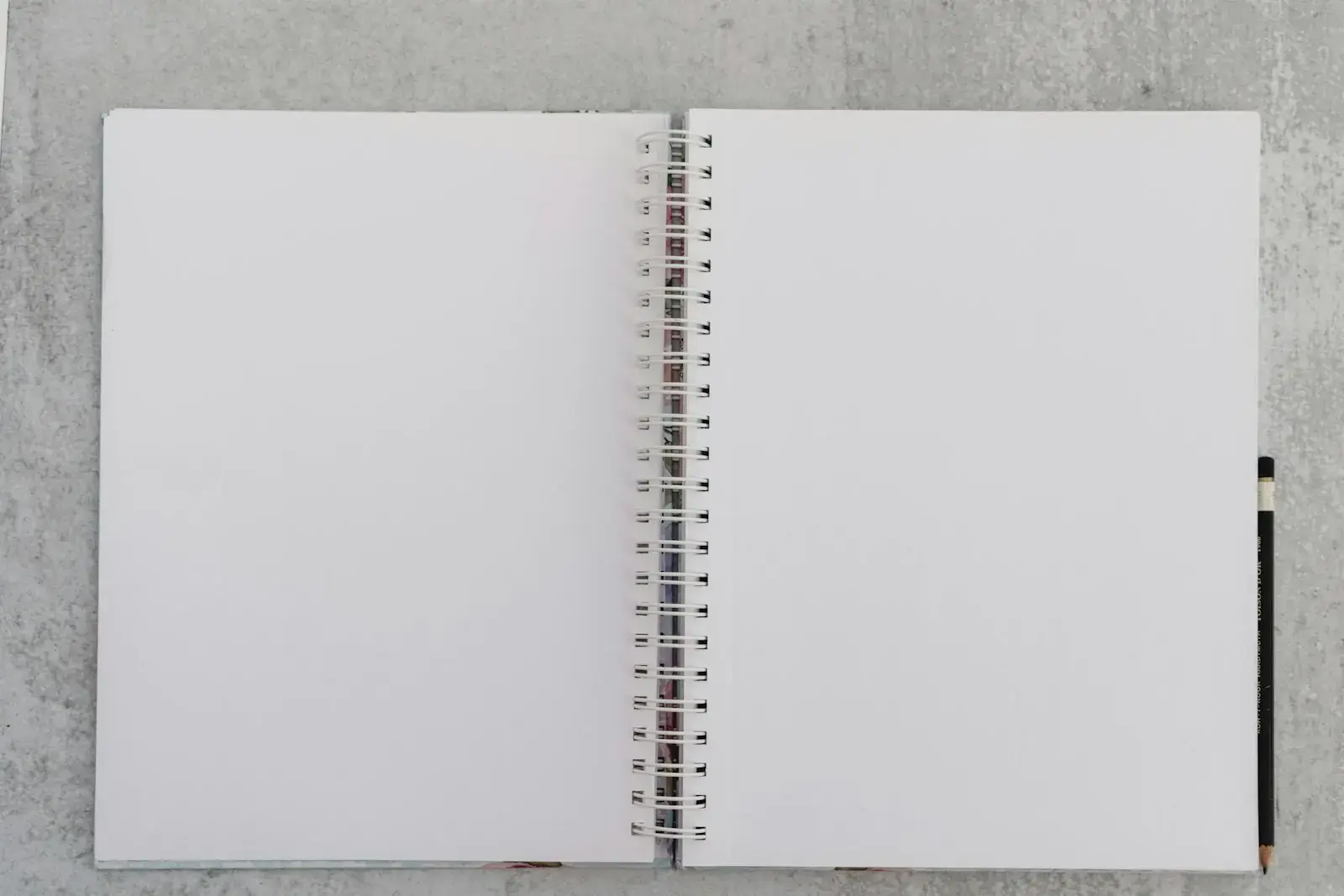 An open blank notebook lying on a grey concrete surface.